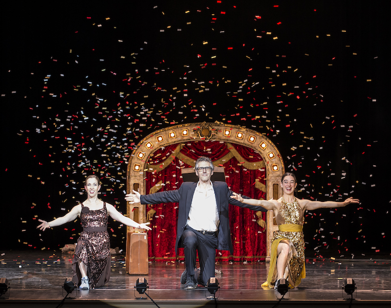 Bass and Bill Barnes flank Ira Glass. They all pose on one knee with their arms outstretched. Colorful confetti flies around them.